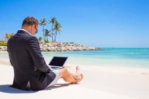 business man with a laptop on a beach in the sunshine, not normal business practice